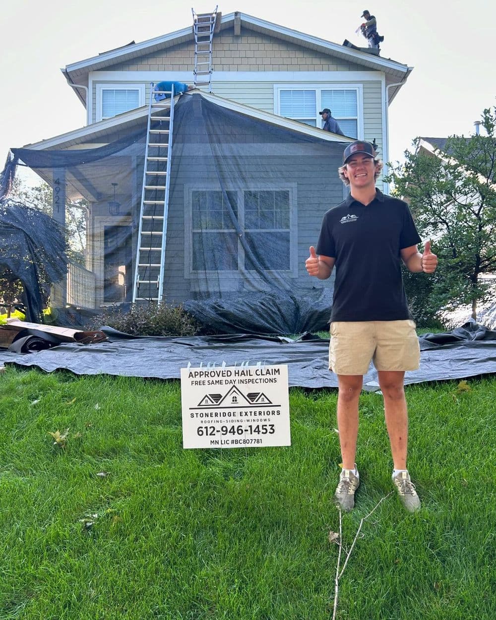 Roofing contractors working on a house, with a sign advertising hail damage inspections.